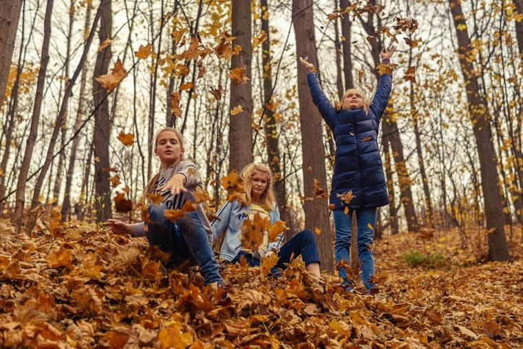 Kinder werfen Herbstlaub